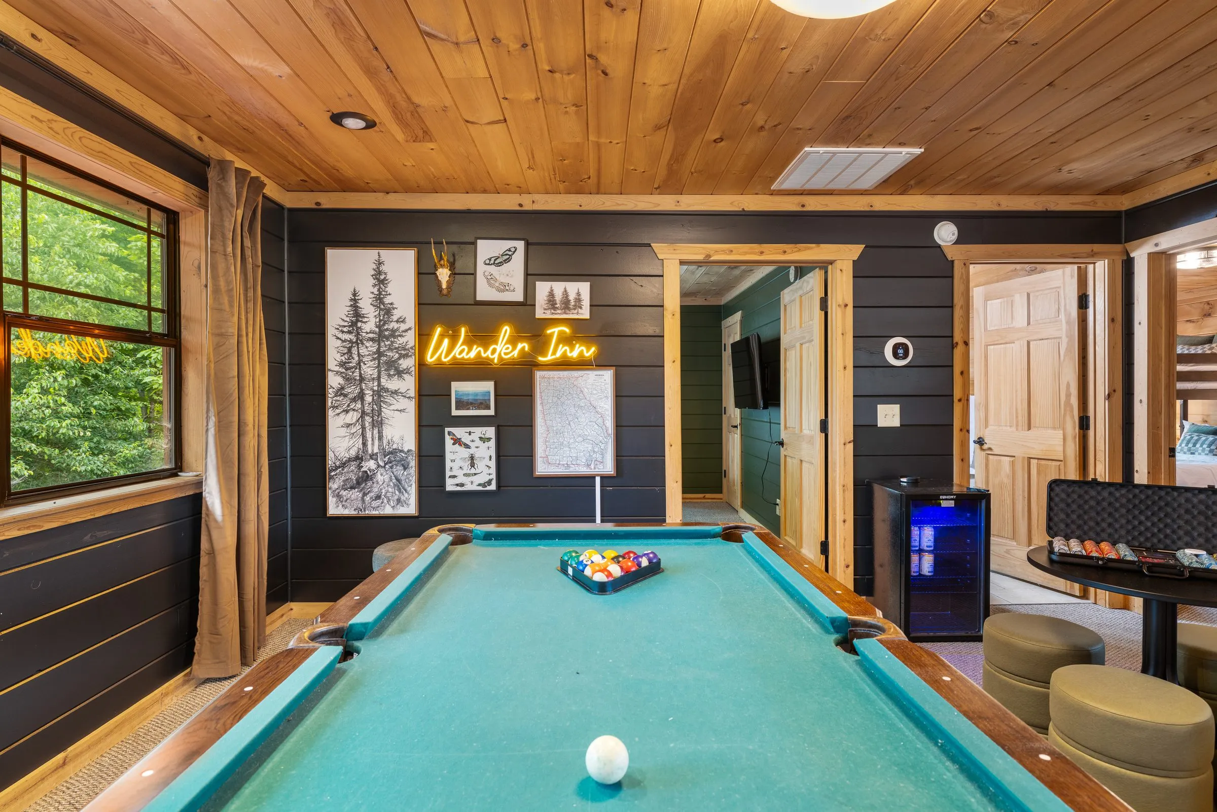 Game room with a pool table under a wood ceiling and a neon Wander Inn sign